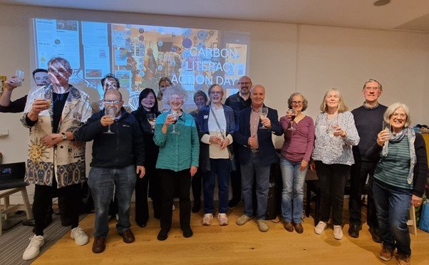 Group photo showing attendees at the 2025 Carbon Literacy Action Day event in front of a large screen