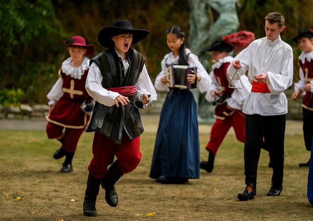 A group of actors moving in their performance, dressed in period costumes