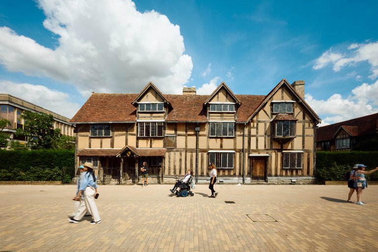 Shakespeare's Birthplace frontage showing people walking in front of the building along Henley Street